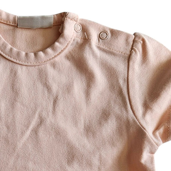 Dit lieve, zalmkleurige t-shirtje met korte mouwen komt uit de Love Garden collectie van Frogs and Dogs. Het t-shirtje is effen van kleur en de mouwtjes zijn speels gerimpeld aangezet. Op de schouder zit een handige drukknoopsluiting. De mouwtjes en onderkant zijn netjes omgezoomd, wat zorgt voor een verzorgde en stijlvolle afwerking.