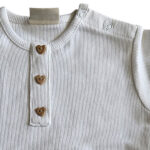 Dit lieve, witte t-shirtje met korte mouwen komt uit de Love Garden collectie van Frogs and Dogs. Het t-shirtje is effen van kleur en is gemaakt van fijne ribstof. Het t-shirtje heeft op de voorzijde een siersluiting met drie knoopjes in de vorm van een hartje. Op de schouder zit een handige drukknoopsluiting. De mouwtjes en onderkant zijn netjes omgezoomd, wat zorgt voor een verzorgde en stijlvolle afwerking.