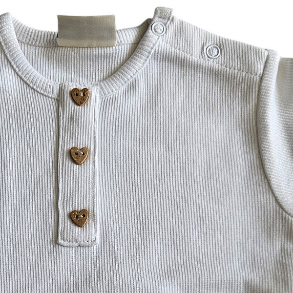 Dit lieve, witte t-shirtje met korte mouwen komt uit de Love Garden collectie van Frogs and Dogs. Het t-shirtje is effen van kleur en is gemaakt van fijne ribstof. Het t-shirtje heeft op de voorzijde een siersluiting met drie knoopjes in de vorm van een hartje. Op de schouder zit een handige drukknoopsluiting. De mouwtjes en onderkant zijn netjes omgezoomd, wat zorgt voor een verzorgde en stijlvolle afwerking.