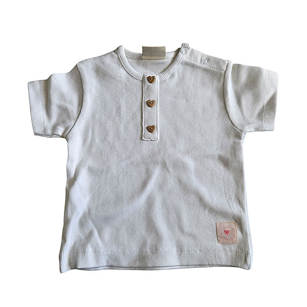 Dit lieve, witte t-shirtje met korte mouwen komt uit de Love Garden collectie van Frogs and Dogs. Het t-shirtje is effen van kleur en is gemaakt van fijne ribstof. Het t-shirtje heeft op de voorzijde een siersluiting met drie knoopjes in de vorm van een hartje. Op de schouder zit een handige drukknoopsluiting. De mouwtjes en onderkant zijn netjes omgezoomd, wat zorgt voor een verzorgde en stijlvolle afwerking.