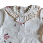 Lief t-shirtje Flo met lange mouw in de zachte tint White Alyssum uit de Summer Flowers-collectie van Frogs and Dogs. Voorzien van een all-over bloemetjesprint in roze en burlwood, een sierlijke rufflerand bij de hals en een praktische drukknoopsluiting op de achterkant. Netjes omgezoomd voor een verzorgde afwerking. Comfortabel en perfect voor zonnige dagen!