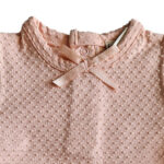 Dit lieve Bubble t-shirtje met korte mouwen in een zachte zalmroze kleur komt uit de Summer Flowers collectie van Frogs and Dogs. Het shirtje is gemaakt van een fijne, luchtige stof met een speels bubbeltjespatroon, wat zorgt voor een subtiele textuur en een extra schattige uitstraling. Een sierlijk strikje op de halsrand aan de voorzijde voegt een charmante en verfijnde touch toe. De gezoomde randen van de mouwtjes zijn afgewerkt met een elegant kanten randje, wat het geheel een romantisch en lieflijk karakter geeft. Aan de achterzijde is een handige drukknoopsluiting aangebracht, zodat het t-shirtje gemakkelijk aan- en uitgetrokken kan worden.