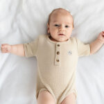 Dit zandkleurige rompertje met wafelstructuur komt uit de All Collection van Frogs and Dogs en is ideaal voor de zomer. Het is gemaakt van een zachte stof en heeft korte mouwen. De voorzijde is voorzien van een sluiting met drie knoopjes, en tussen de beentjes zit een drukknoopsluiting. Het rompertje kan los gedragen worden bij warm weer of gecombineerd worden met een vestje op koelere dagen.