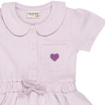 Dit mooie jurkje in de kleur Lavender Fog komt uit de Beautiful Hearts collectie van Frogs and Dogs. Het jurkje heeft een schattig kraagje en een drukknoopsluiting aan de voorzijde. Op het borstzakje prijkt een paars geborduurd hartje. De mouwtjes zijn licht gepoft en het rokje heeft een speelse, gerimpelde zoom. In de taille bevindt zich een elastische rand met een strikje, wat de jurk een extra charmante uitstraling geeft. Het rokje is voorzien van 2 steekzakjes.