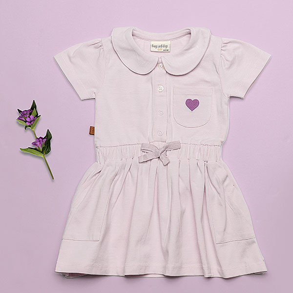 Dit mooie jurkje in de kleur Lavender Fog komt uit de Beautiful Hearts collectie van Frogs and Dogs. Het jurkje heeft een schattig kraagje en een drukknoopsluiting aan de voorzijde. Op het borstzakje prijkt een paars geborduurd hartje. De mouwtjes zijn licht gepoft en het rokje heeft een speelse, gerimpelde zoom. In de taille bevindt zich een elastische rand met een strikje, wat de jurk een extra charmante uitstraling geeft. Het rokje is voorzien van 2 steekzakjes.
