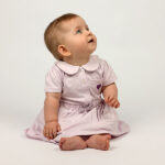 Dit mooie jurkje in de kleur Lavender Fog komt uit de Beautiful Hearts collectie van Frogs and Dogs. Het jurkje heeft een schattig kraagje en een drukknoopsluiting aan de voorzijde. Op het borstzakje prijkt een paars geborduurd hartje. De mouwtjes zijn licht gepoft en het rokje heeft een speelse, gerimpelde zoom. In de taille bevindt zich een elastische rand met een strikje, wat de jurk een extra charmante uitstraling geeft. Het rokje is voorzien van 2 steekzakjes.