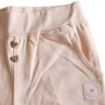 Dit schattige zalmkleurige korte broekje - short - is perfect voor zomerse dagen. Het heeft een elastische tailleband, sierknoopjes en een elegant kanten randje voor een speelse uitstraling. Een comfortabele en stijlvolle keuze voor je kleintje!