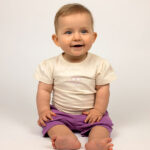 Crèmekleurig baby t-shirtje met lavendelkleurig hartje, pofmouwtjes en drukknoopsluiting uit de Frogs and Dogs collectie.