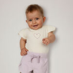 Crèmekleurig baby t-shirtje met lavendelkleurig hartje, pofmouwtjes en drukknoopsluiting uit de Frogs and Dogs collectie.