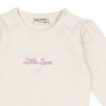 Crèmekleurig baby t-shirtje met lange mouw, tekst ‘Little Love’, lila hartje en pofmouwtjes uit de Frogs and Dogs collectie.