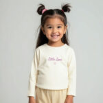 Crèmekleurig baby t-shirtje met lange mouw, tekst ‘Little Love’, lila hartje en pofmouwtjes uit de Frogs and Dogs collectie.