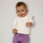 Crèmekleurig baby t-shirtje met lange mouw, tekst ‘Little Love’, lila hartje en pofmouwtjes uit de Frogs and Dogs collectie.