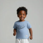 Blauw baby t-shirtje voor jongens met dolfijnenprint uit de Sun and Sand collectie van Frogs and Dogs. Met korte mouw en schouderknoopjes.