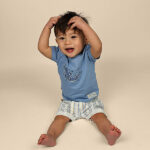 Blauw baby t-shirtje voor jongens met dolfijnenprint uit de Sun and Sand collectie van Frogs and Dogs. Met korte mouw en schouderknoopjes.