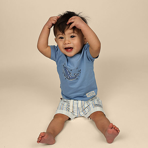 Blauw baby t-shirtje voor jongens met dolfijnenprint uit de Sun and Sand collectie van Frogs and Dogs. Met korte mouw en schouderknoopjes.