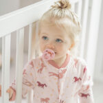 Roze Frogs and Dogs baby onesie met paardenprint en roze manchetten.