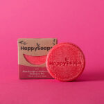 Happysoaps You’re One in a Melon Shampoo Bar in roze kleur met verpakking op roze achtergrond.