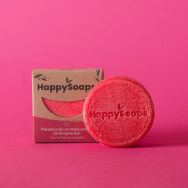 Happysoaps You’re One in a Melon Shampoo Bar in roze kleur met verpakking op roze achtergrond.
