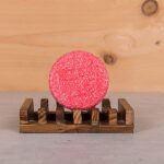 Happysoaps You’re One in a Melon Shampoo Bar in roze kleur met verpakking op roze achtergrond.
