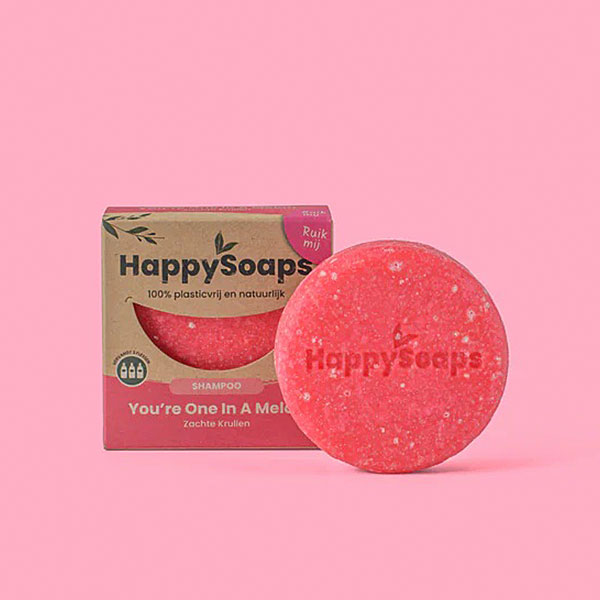 Happysoaps You’re One in a Melon Shampoo Bar in roze kleur met verpakking op roze achtergrond.